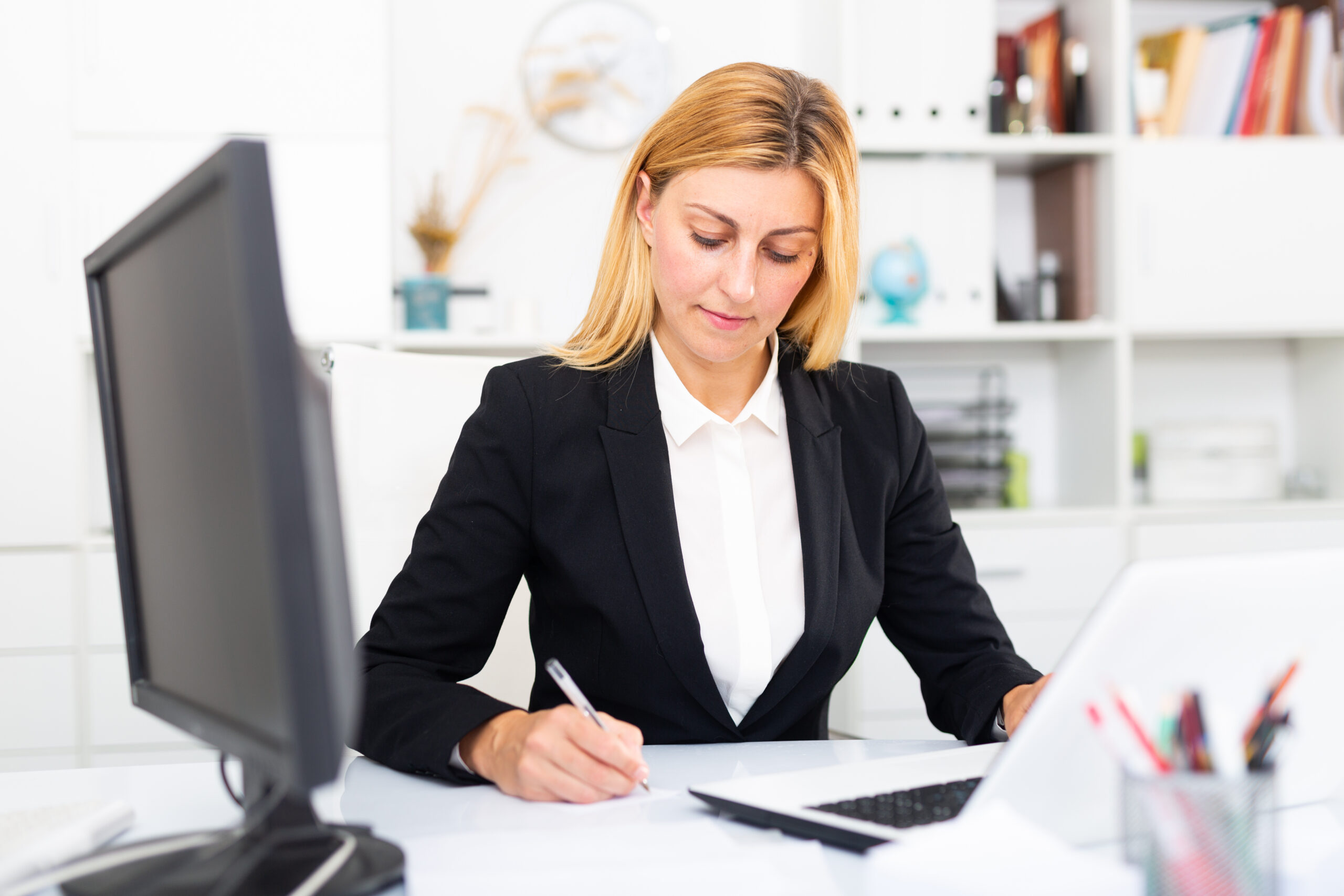 Kobieta przy biurku podpisuje dokumenty prowadząc własną firme